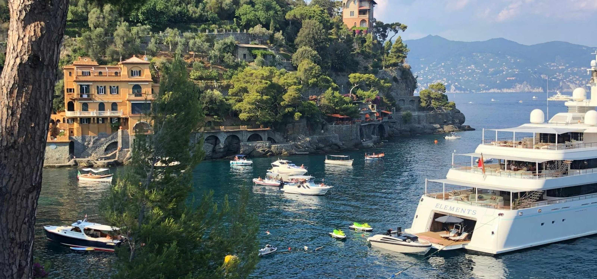Luxury boats docked in a scenic harbor with mountains in the background