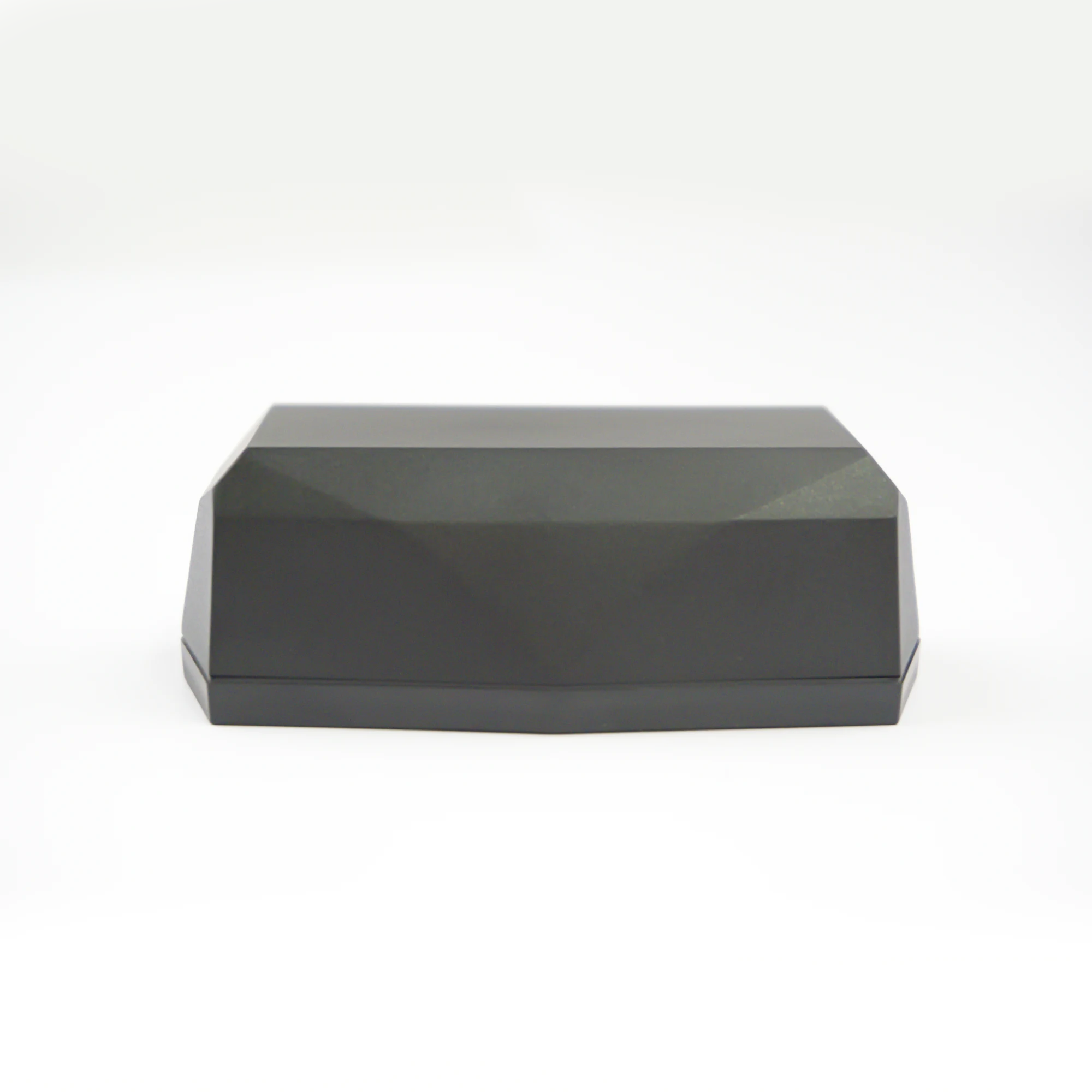 Side view of Gemstone GPS tracker; a black faceted geometric shape, on a clean white studio background.